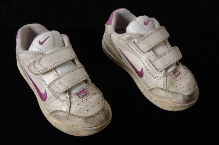 Paar witte sneakers, merk Nike, met klittenbandsluiting en roze accenten