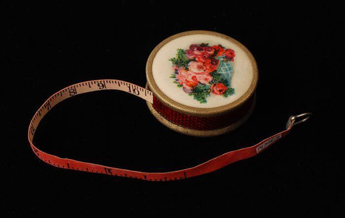 Klein rond doosje met opgerold meetlint, bovenzijdemand met roze, onderzijdefelroze, zijderood