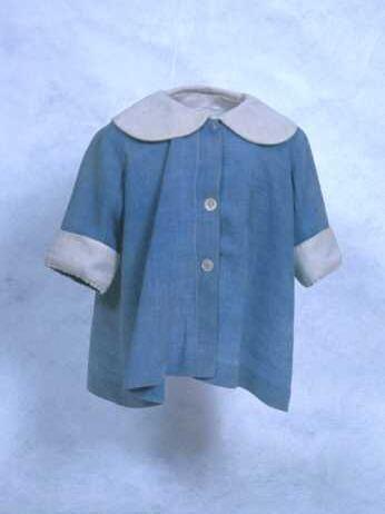 Kinderjas of kinderjurk van blauw katoen gerend model met brede manchetten en platte kraag van wit …