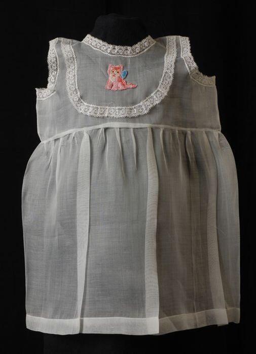 Babyjurk, mouwloos schortmodel van transparant wit nylonmet geborduurd roze poesje, 'Femifra' model…