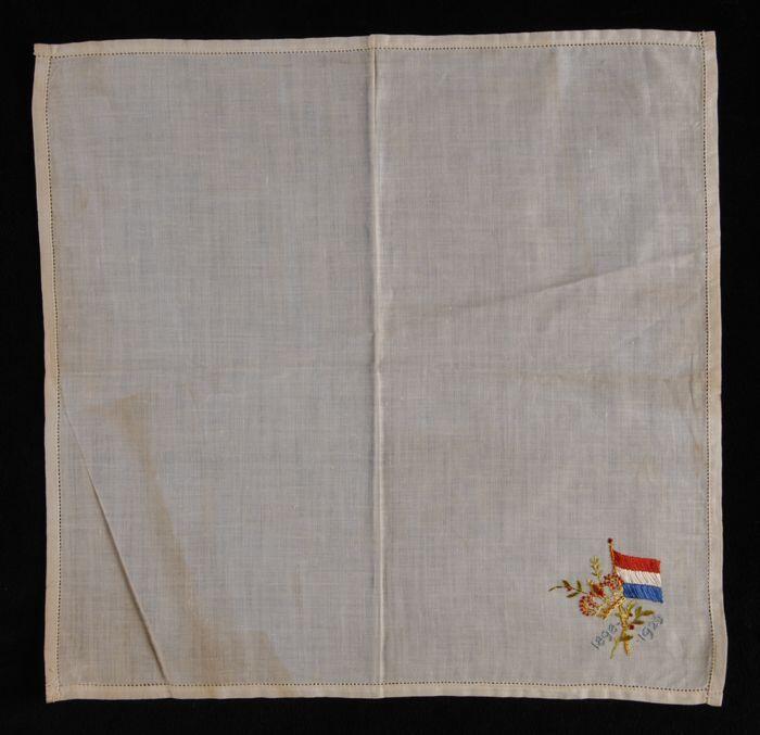 Vierkante herinneringsdoek, van wit linnen met in één hoek veelkleurig borduursel, Nederlandse vlag…