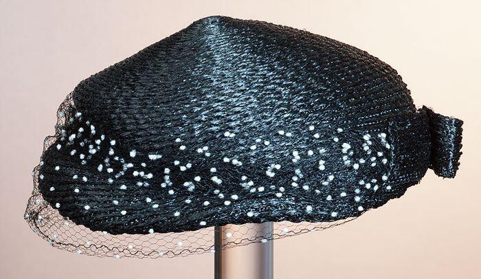 Dop, rond model zonder rand, donkerblauw raffia met platte strik en zwart voile met witte nopjes…