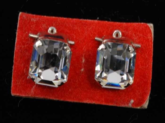 Eén paar oorbellen, clip met rechthoekige kunstdiamant in zilverkleurige vattin, op rood…