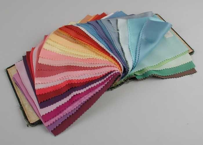 Stalenboek met 44 kleurige staaltjes voeringstof, zwart kartonnen band met schroeven