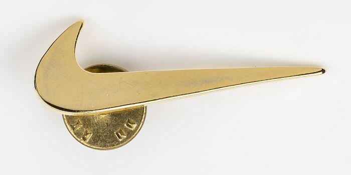 Goudkleurig metalen speldje in de vorm van 'Nike'-logo