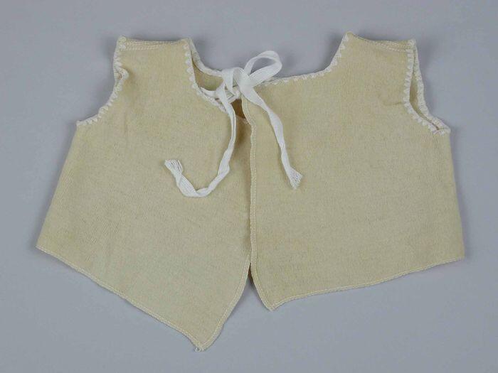 Babyhemd of boorlinghemd van zandgeel tricot, ronde hals, armsgaten met wit sierstiksel, hals…