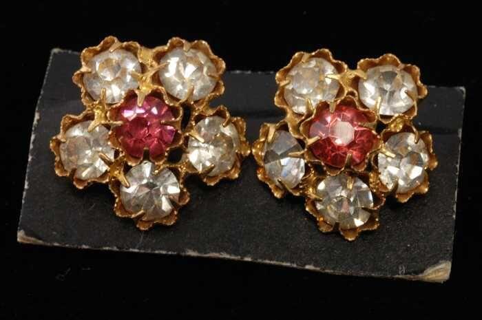 Eén paar oorbellen, clip met kleine roze en witte kunstdiamantjes in bloemvormige zettin, op zwart…