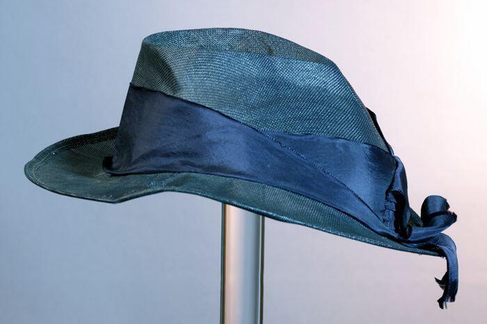 Dameshoed van donkerblauw gaas, gedeukte bol en breed donkerblauw lint rondom de bol met strik