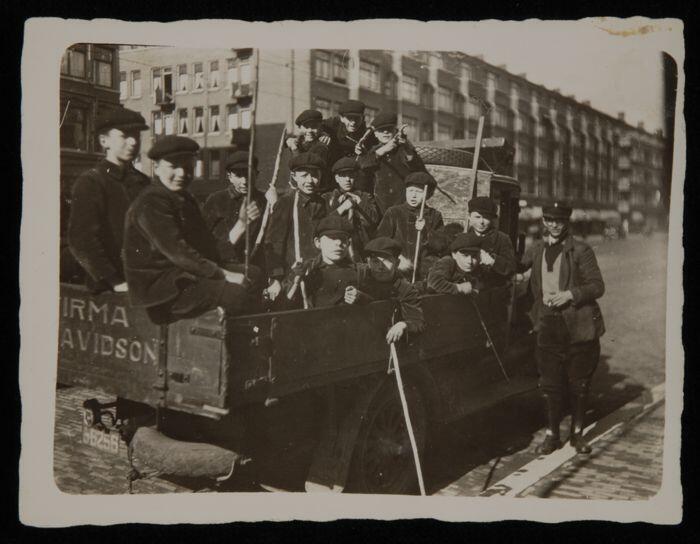Zwart-wit foto van 13 weesjongens van het Gereformeerd Burger Weeshuis in de laadbak van een…