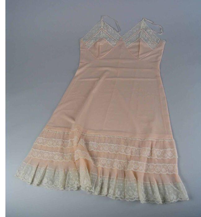 Knielange onderjurk van transparant roze nylontricot met geplisseerde randen langs de onderzijde en…