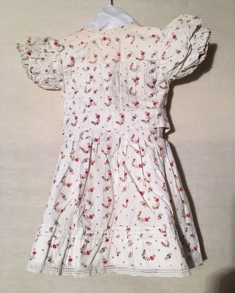 Kinderjurkje, wit katoen bedrukt met rood/bruin/beige bloemmotief