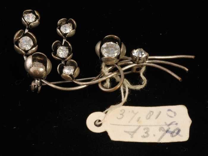 Broche, zilverkleurig metaal met bloemvormpjes met kunstdiamantjes, kapper Van Vliet