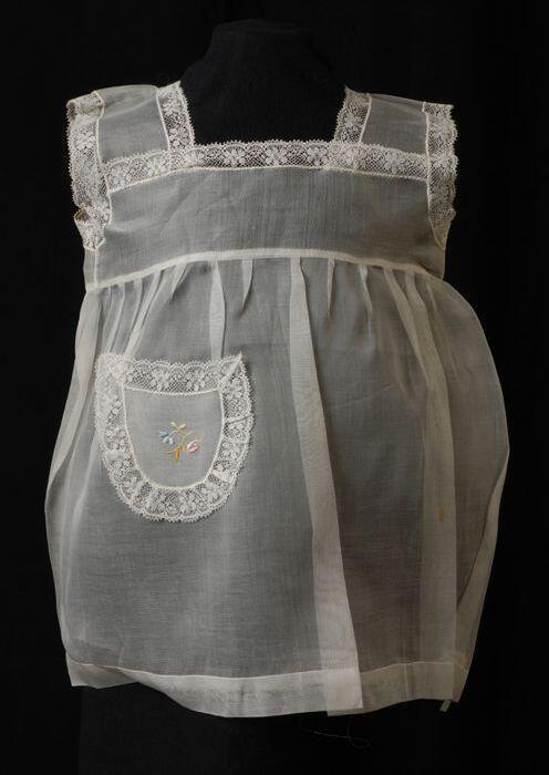 Babyjurk, mouwloos schortmodel van transparant wit nylonmet wit kant en geborduurd bloemetje, …
