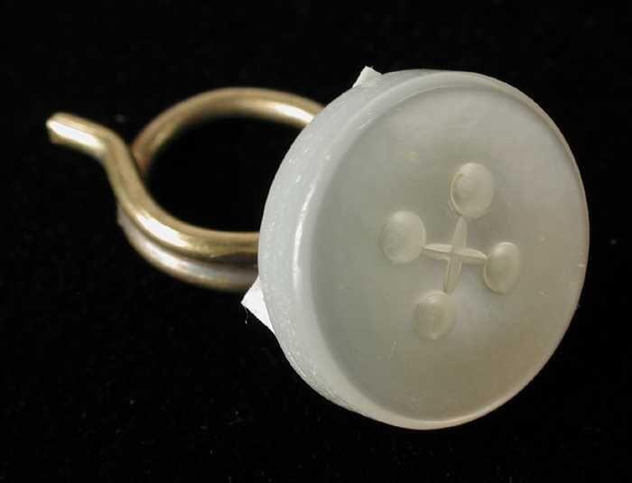 Boordenknoop van kunststofen parelmoer-imitatie met metalen 'sleutelring' aan achterzijde