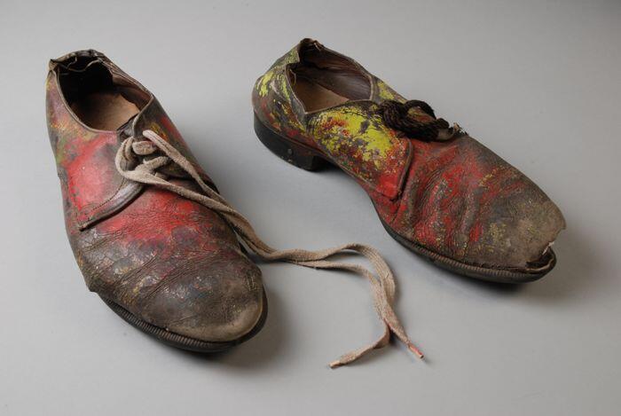 Paar leren heren veterschoenen beschilderd met rode, gele en groene verf en verschillende veters,…