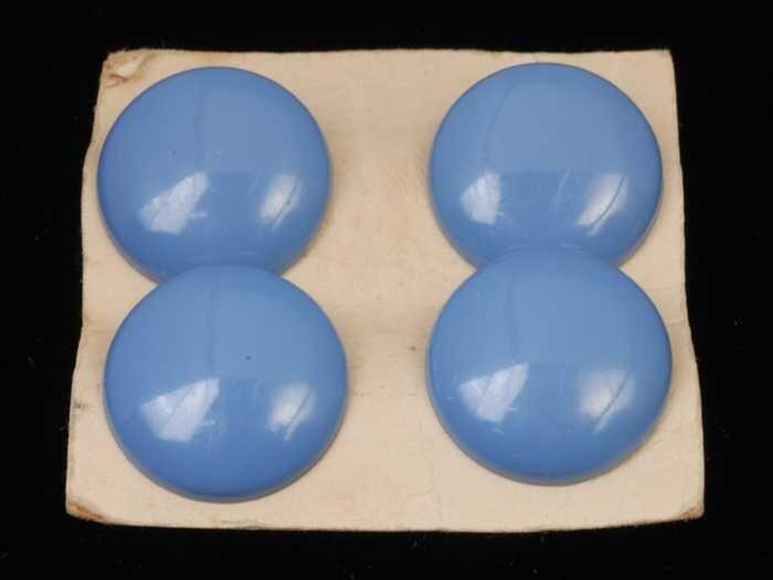 Twee paar oorbellen, clip met ronde blauwe plastic knop, op karton, kapper Van Vliet