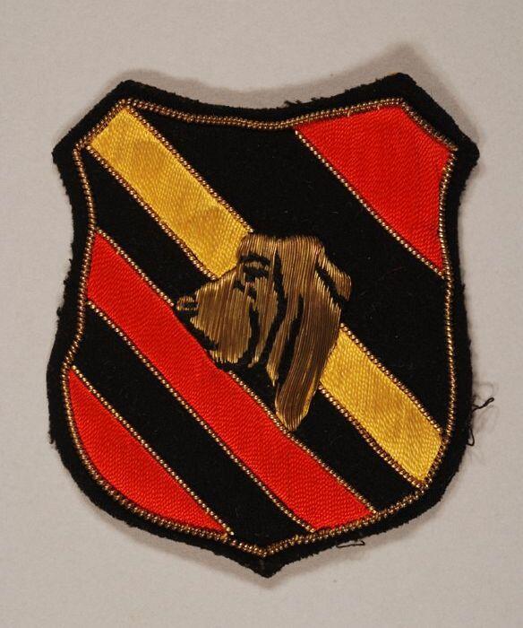 Stoffen badge, gouddraad hondenkop op schildvormig zwarte ondergrond met gouddraad opgestikt…