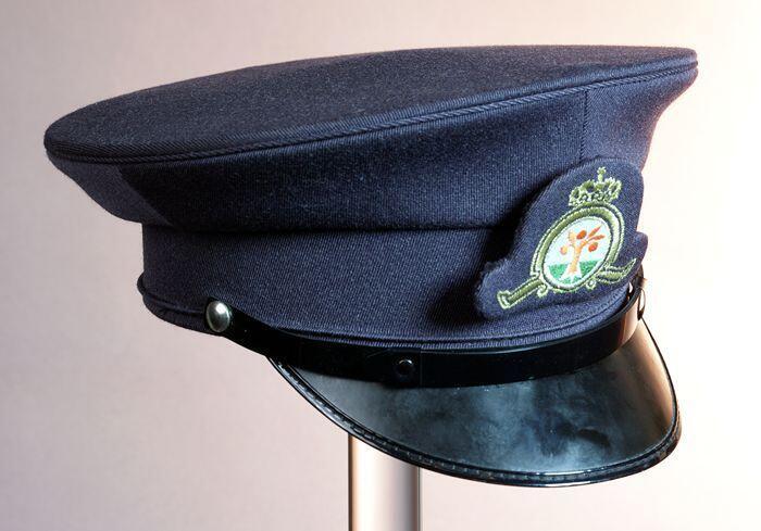 Platte uniformpet, grijsblauw keper met glanzend zwarte klep en embleem met logo Oranjeboom