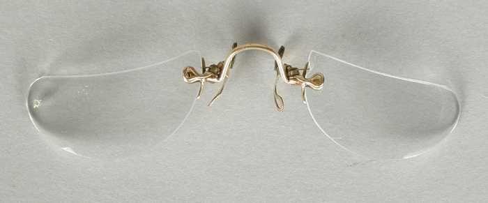 Knijpbril of pince-nez met halvemaan-vormige glazen op sterkte en een vergulde neusbrug en…