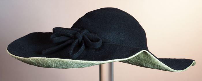 Dameshoed, ovaal, zwart vilt, onderzijdegladstro, hoedrand breder aan één zijde strik, met label