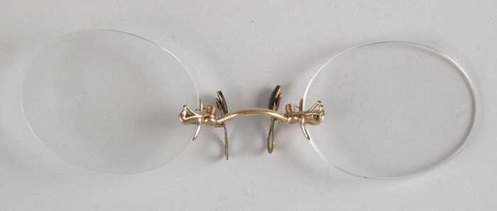 Knijpbril of pince-nez zonder montuur, met ovale glazen op sterkte, goudkleurige brug en flexibele…
