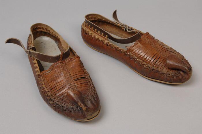 Bruine leren moccasins met opstaande neus en voorvoet opgebouwd uit smalle strookjes leer,…