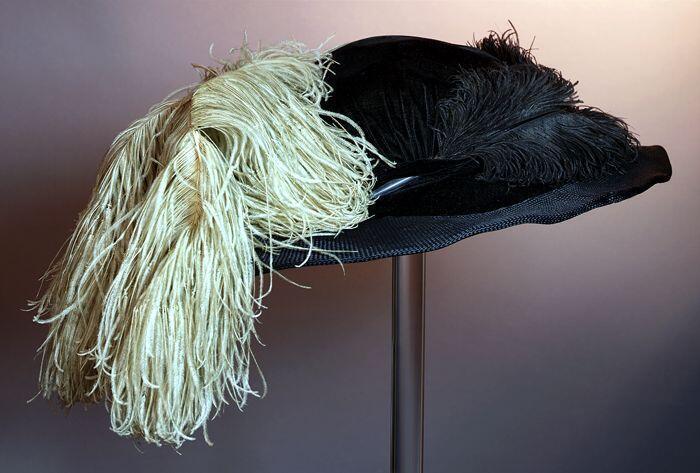 Grote ovale dameshoed van zwart fluweel met rijkelijke garnering van zwart en beige struisveren
