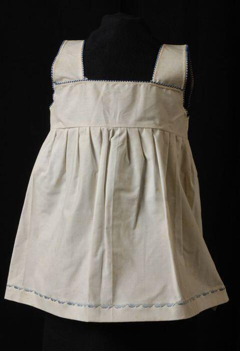 Babyjurk, mouwloos schortmodel, 'Femifra', afgewerkt met blauw biesje langs hals en mouw, blauw…