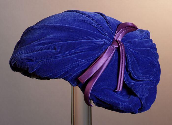 Kapje van blauw gedrapeerd fluweel, velours met plat strik van paars satijnband