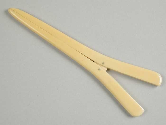 Handschoenrekker van ivoor, twee spits toelopende poten met korte veer