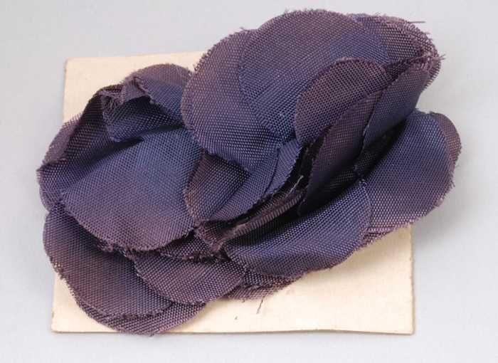 Paar oorbellen, clip met donkerblauwe kunstzijdebloem, op karton, kapper Van Vliet
