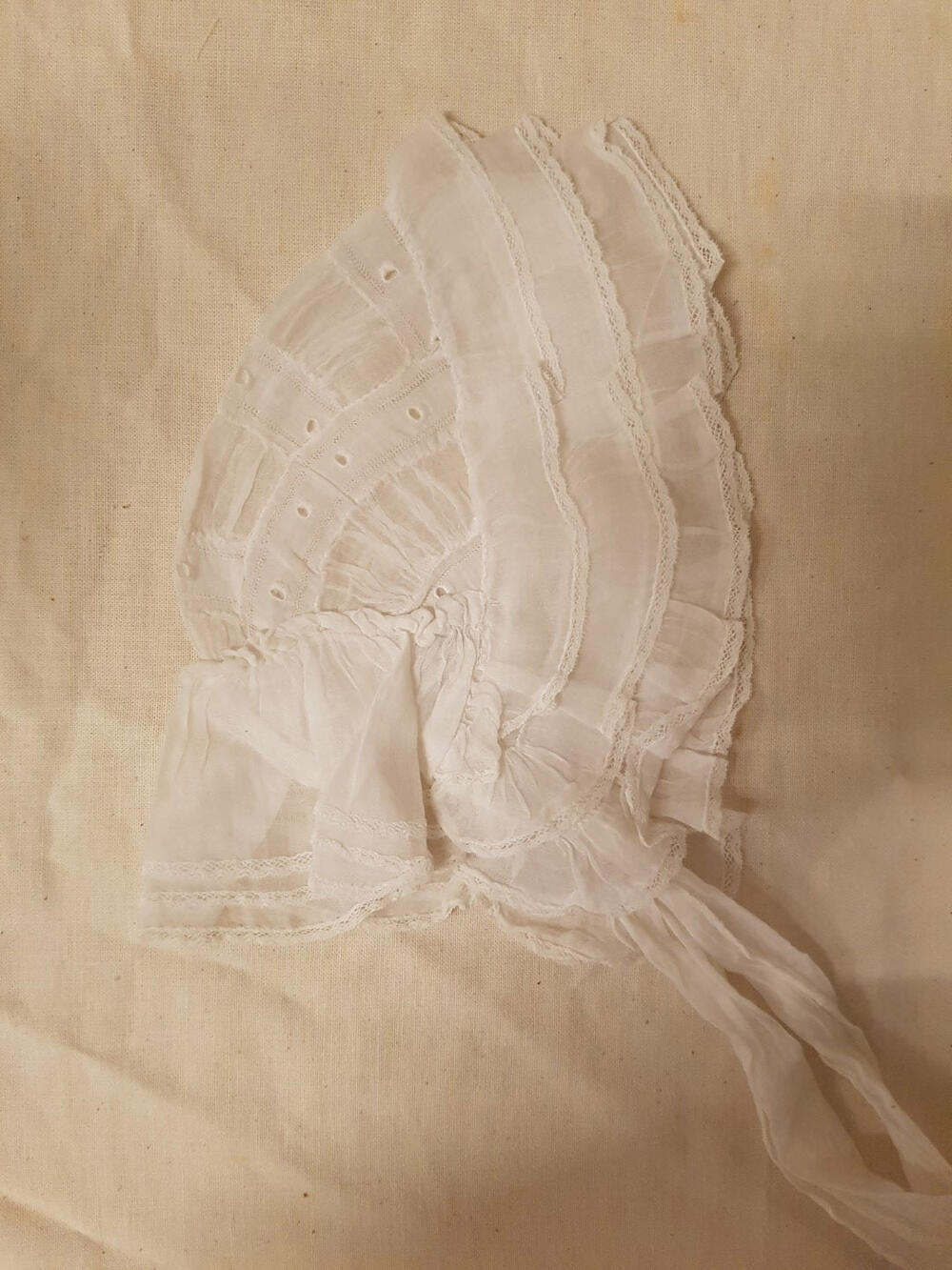 Babymuts, wit neteldoek, geborduurd met gaatjes en open naadjes