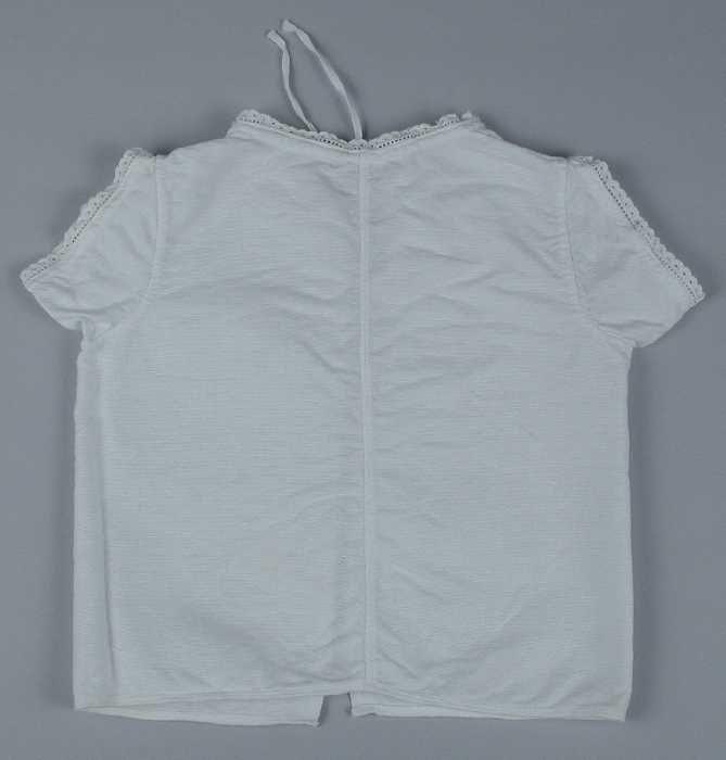 Babyhemd van wit linnen smalle rand broderie anglaise langs hals en korte mouwen, koordje door…
