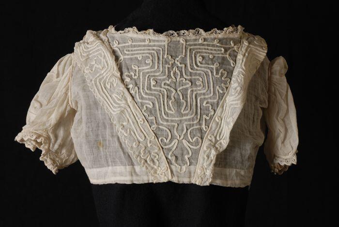 Lijfje van een doopjurk, crèmekleurig batist met soutache op het voorpand, kant langs de rechte…