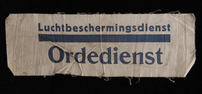 Onafgewerkte mouwband, wit katoen met opdruk in donkerblauw, "Luchtbeschermingsdienst Ordedienst",…