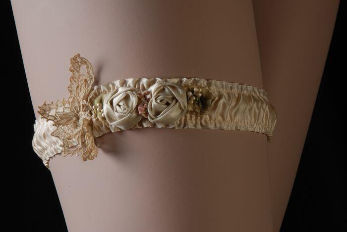 Kousenband van crèmekleurig gerimpeld zijde op katoenen ondergrond met decoratie van zijde rozen en…