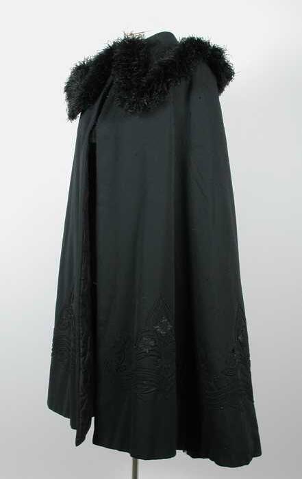 Lange cape van gewatteerde zwarte wol brede kraag met soutache en maraboeveertjes, soutache langs…