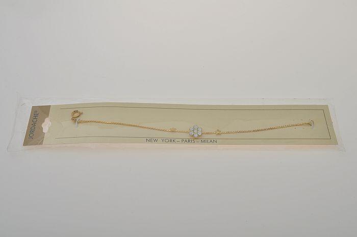Goudkleurig metalen armbandje in verpakking, in het midden een bloemvorm van zeven strass-steentjes…