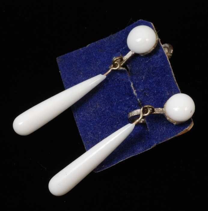 Paar oorbellen, draaihaakje met dunne pegel van wit glas op blauw fluweelkarton, kapper Van Vliet
