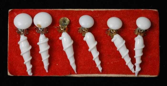 Drie paar oorbellen, clips met pegels met een spiraal van wit glas op rood fluweelkarton, kapper…