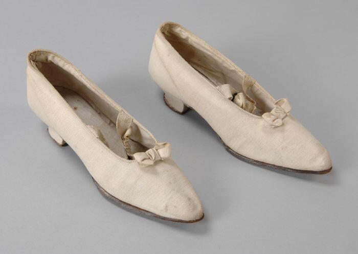 Roomwitte katoenen pumps met strikjes op neus en elastische wreefband, kleine ingebogen hak