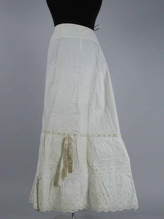 Lange wijduitlopende onderrok van wit katoen brede sierstrook met oprijgjes, broderie anglaise…