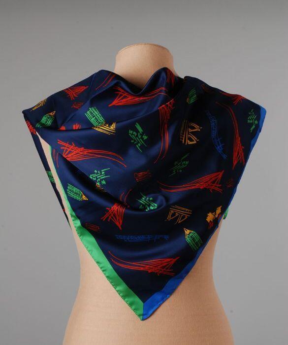 Vierkante shawl, donkerblauw fond met gestileerde tekeningen in rood, groen, geel en blauw die…