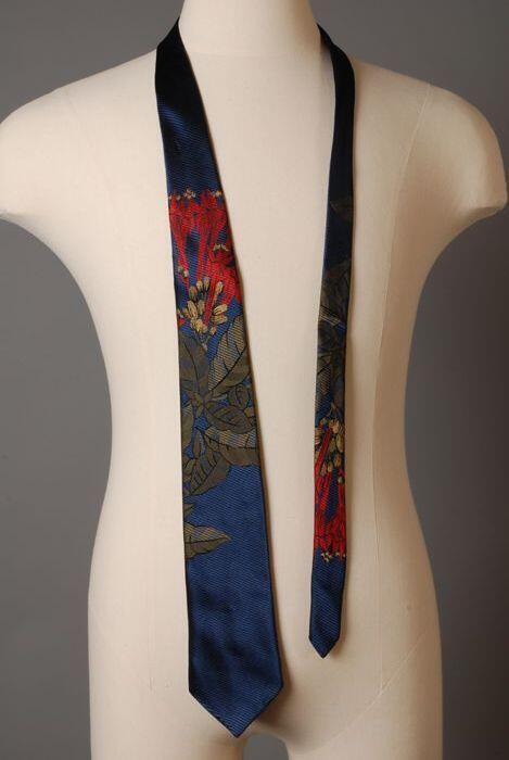 Stropdas, zelfbinder, van kunststof met bladeren en bloemen in groen en rood op donkerblauwe…