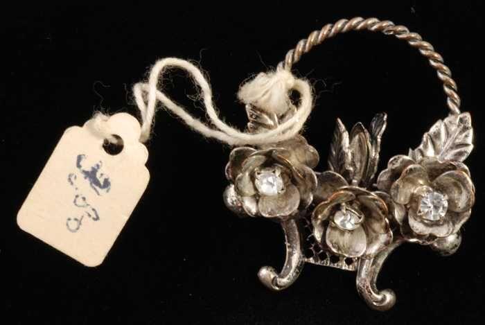 Broche, zilverkleurige metalen hengselmandje met blaadjes en bloemen en kunstdiamantjes, kapper Van…