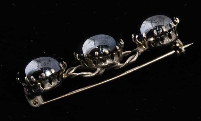 Broche, zilverkleurige metalen basis met drie donkere metalliek glanzende ronde bolle stenen (?),…