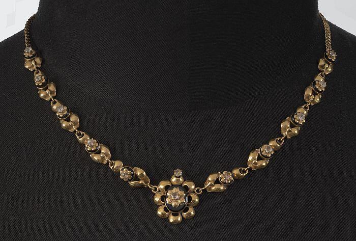 Gouden schakelketting, met zwarte steen ingelegd, erop gouden zettin met geslepen diamant