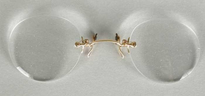 Knijpbril of pince-nez met vrijwel ronde glazen op sterkte zonder montuur, met goudkleurige metalen…
