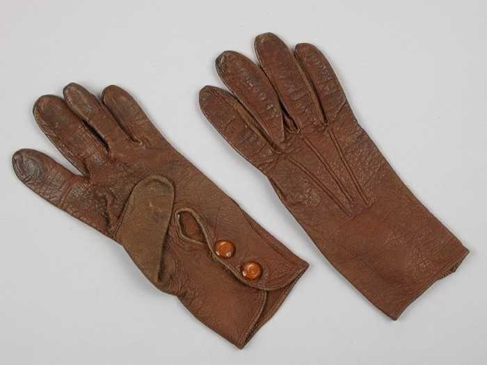 Paar korte kinderhandschoenen van bruin leer met transparant oranje drukknopen