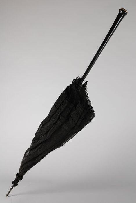 Zwarte rouwparasol met rechte steel en grijs metalen sierbeslag op de knop